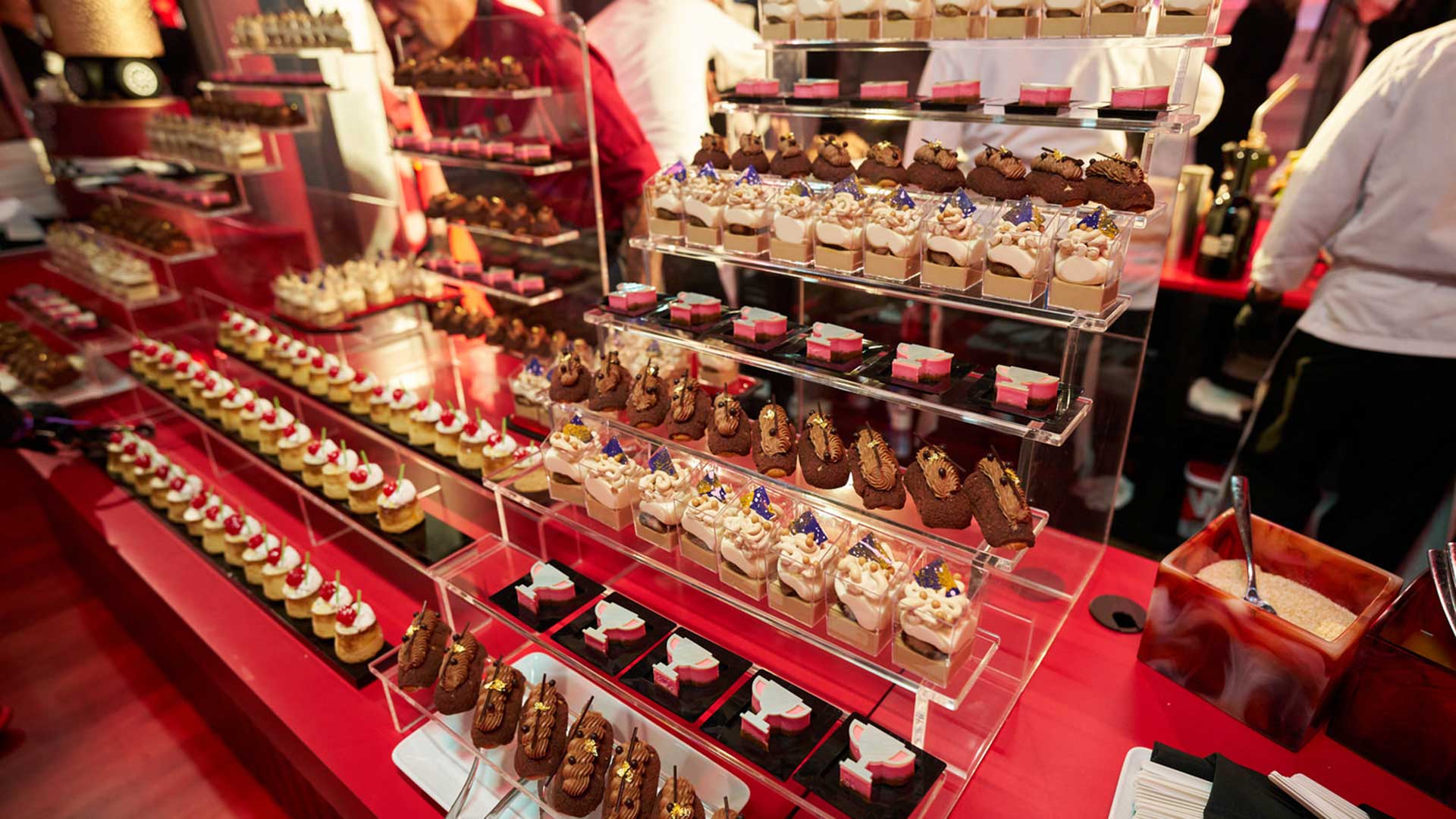 Assortment of treats presented on clear platforms atop a red tabling area