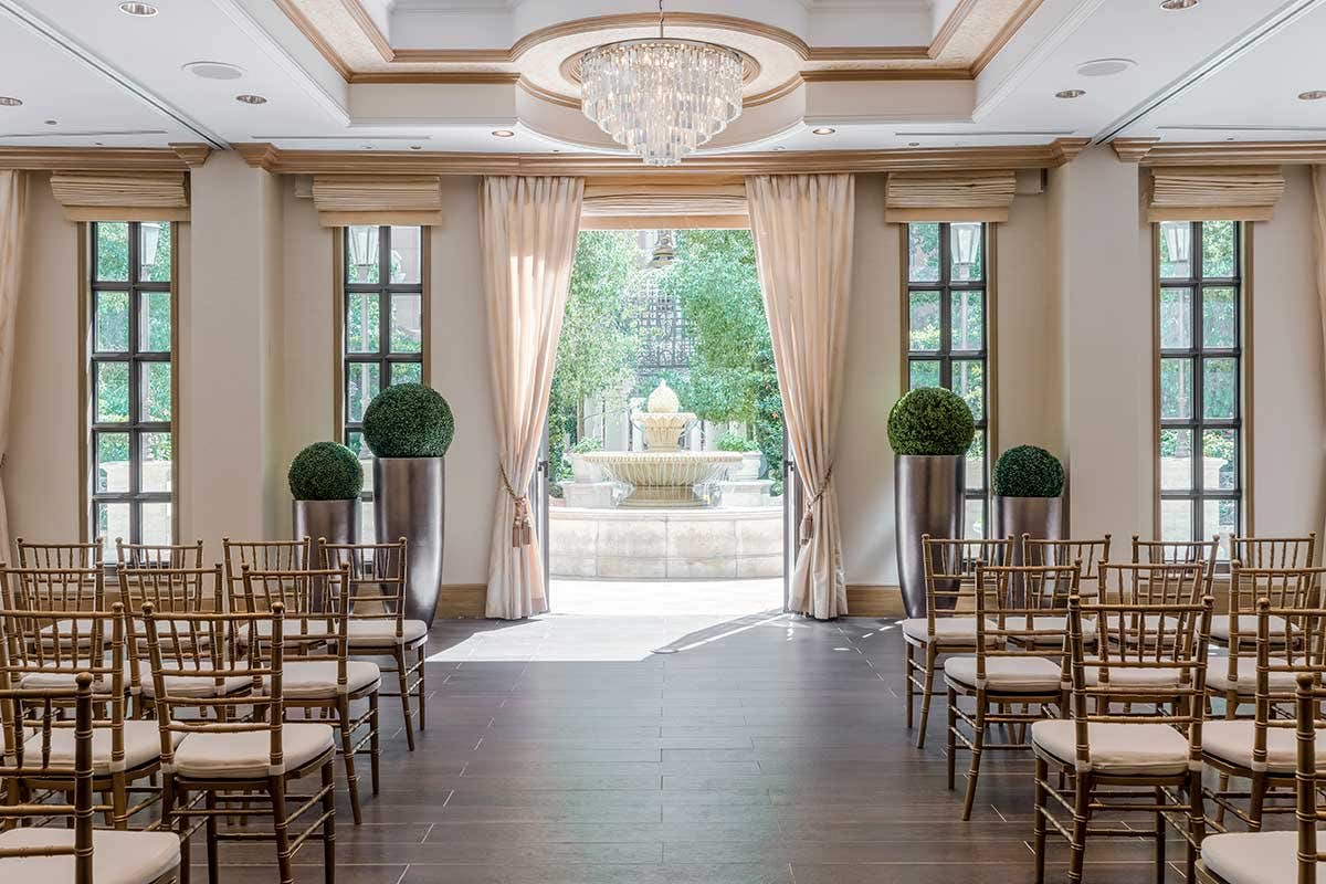 A wedding chapel with chairs set up and doors open to a terrace with a fountain.